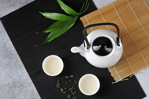 Dos tazas blancas de té verde y una tetera en servilletas de bambú. Concepto de ceremonia del té. Primer plano. Vista desde arriba
. - Foto, imagen