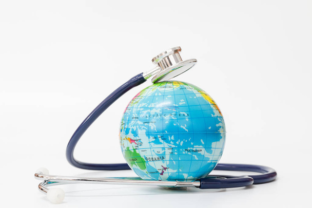 Stethoscope wrapped around globe on white background. - Fotoğraf, Görsel