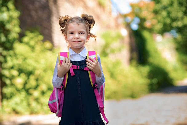 Smiling student girl wearing school backpack. Portrait of happy Caucasian young girl outside the primary school. Smiling schoolgirl looking at camera. - Foto, imagen