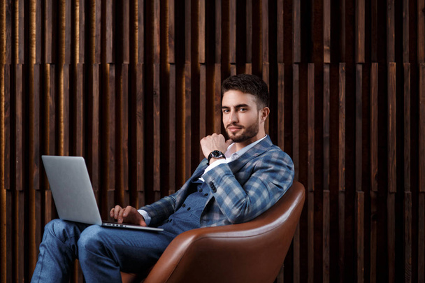 Young successful businessman is working behind a laptop while sitting in a loft office. bearded man working on a laptop - Foto, afbeelding