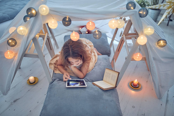 Piccola bambina di 10 anni utilizzando tablet sotto la sua tenda fatta in casa in
 - Foto, immagini