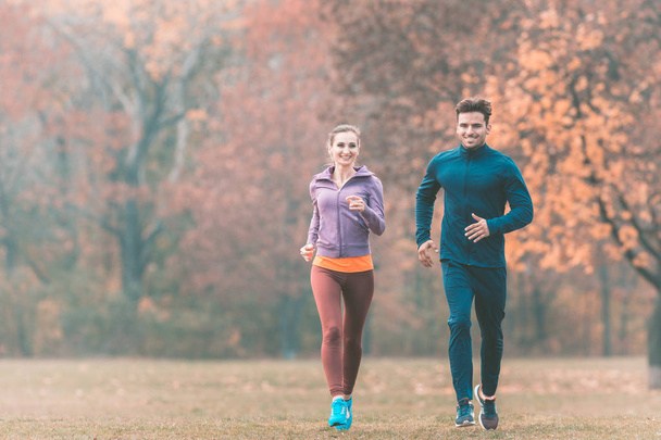 Harika sonbahar manzarası olan bir çift daha iyi spor yapmak için koşuyor. - Fotoğraf, Görsel