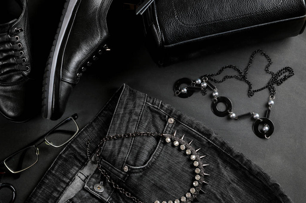 Ropa y accesorios. Ropa de mujer y accesorios en un estilo negro sobre un fondo negro. Bolsa, espera, chaqueta. Acostado. Vista superior
 - Foto, Imagen
