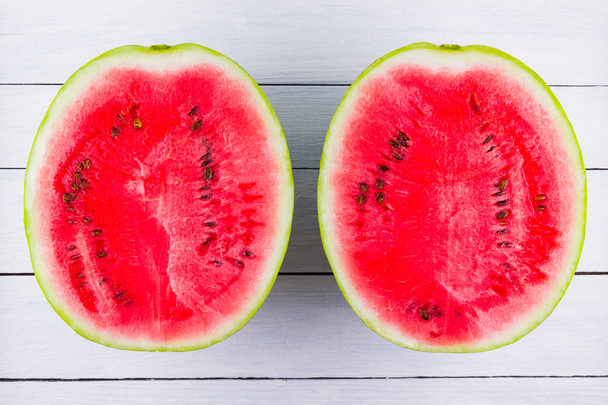 Half of watermelon on white background. Sliced watermelon on wooden boards. Healthy food for vegan. Top view - 写真・画像
