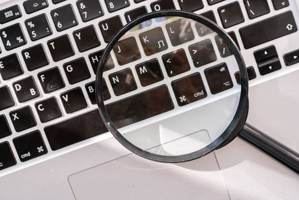 a magnifying glass on the keyboard, searching on the internet concept - Fotografie, Obrázek