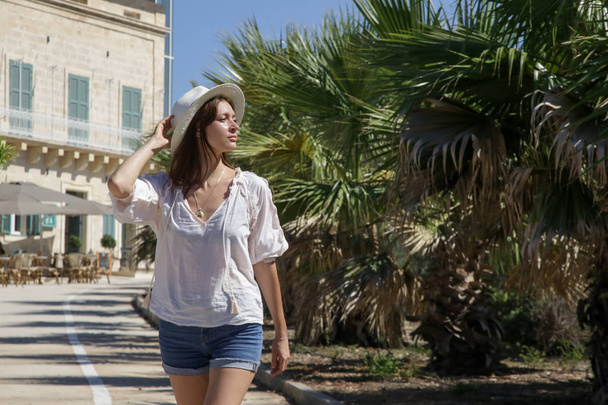 ein lässiges Modeporträt einer jungen Touristin im Sommeroutfit, die auf der Straße spaziert, Sommerferienkonzept - Foto, Bild