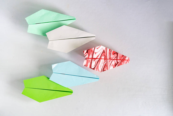 een uniek papieren vliegtuig met een aantal regelmatige, leiderschap concept op de tafel - Foto, afbeelding