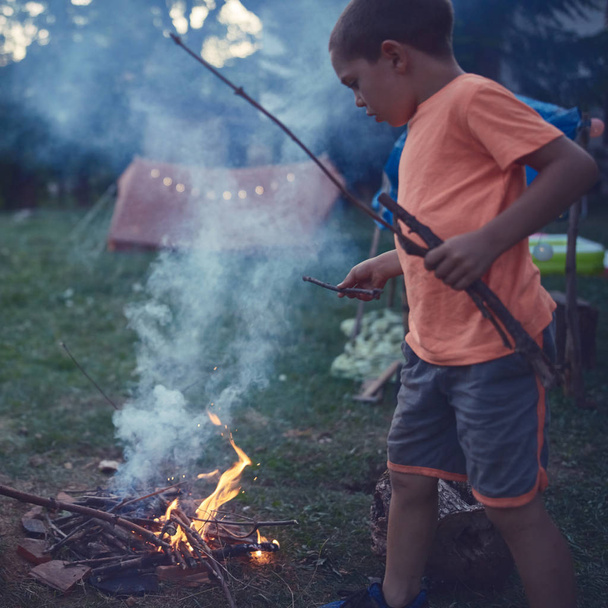 Kleines Junge Kind macht Lagerfeuer auf einer Wiese. - Foto, Bild