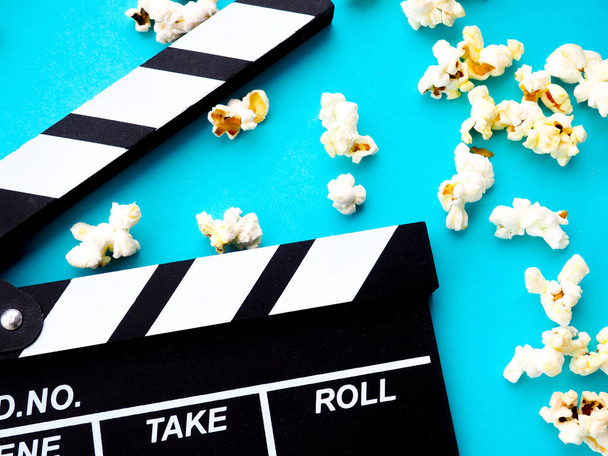 Popcorn and clapperboard on blue background. the concept of movi - Photo, Image