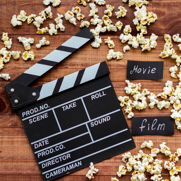Den Film anschauen. Film Clapperboard und Popcorn auf blauem Holztisch Hintergrund Ansicht Kopierraum - Foto, Bild