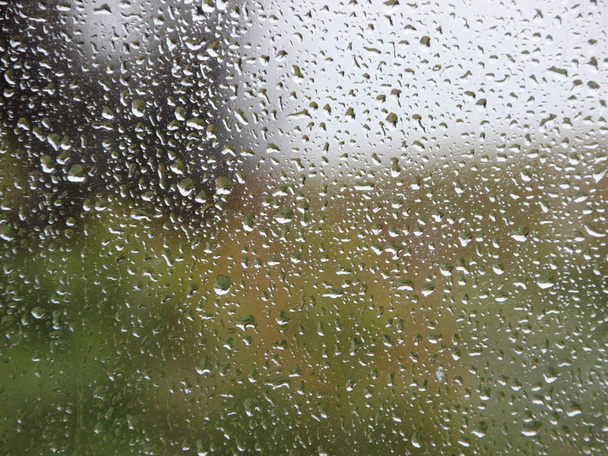 Σταγόνες βροχής στο παράθυρο με φόντο τον πράσινο κήπο - Φωτογραφία, εικόνα