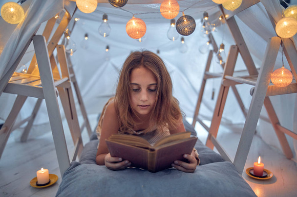 Маленькая 10-летняя девочка читает классическую книгу под домашней работой
 - Фото, изображение