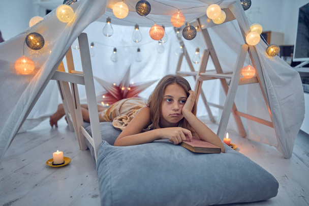 Pequeña niña de 10 años leyendo un libro clásico bajo su casa
 - Foto, Imagen