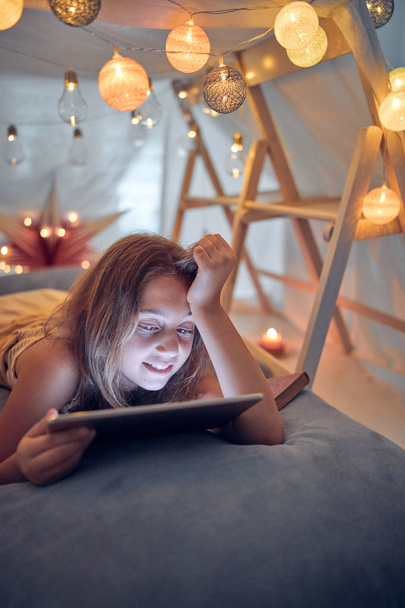 Pequena menina de 10 anos usando tablet sob sua barraca caseira em
 - Foto, Imagem