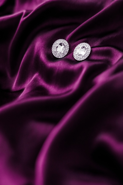 Luksusowe kolczyki diamentowe na ciemnoróżowej tkaniny jedwabnej, święto glamou - Zdjęcie, obraz