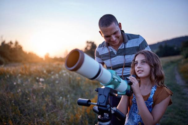 Ojciec i córka obserwujący niebo teleskopem. - Zdjęcie, obraz