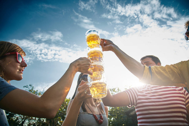 Group of young people enjoying and cheering beer outdoors. - 写真・画像