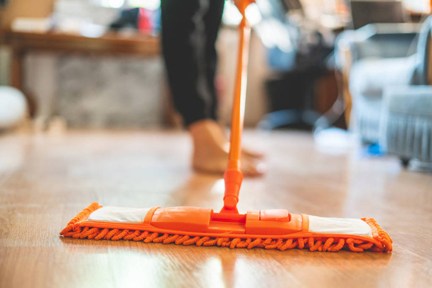 hombre soltero sosteniendo una fregona y limpiando el suelo laminado en casa - Foto, imagen