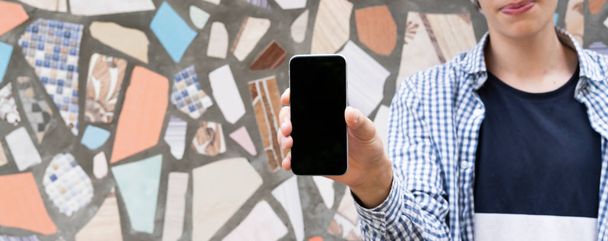 Hand hält ein schwarzes Smartphone mit Kopierraum-Design-Attrappe - Foto, Bild