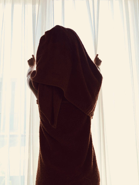 Kobieta z ręcznikiem przed oknem i zasłoną. - Zdjęcie, obraz