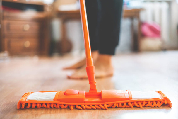 único homem segurando uma esfregona e limpando o piso laminado em casa - Foto, Imagem