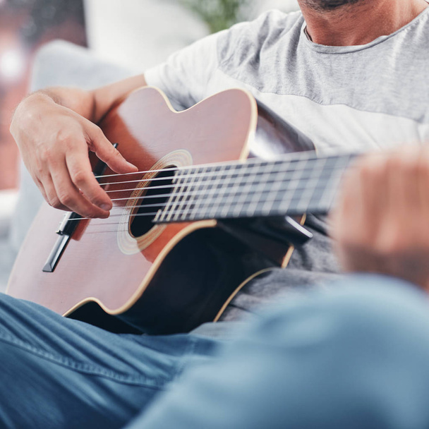 Man playing acoustic guitar in the living room. - 写真・画像