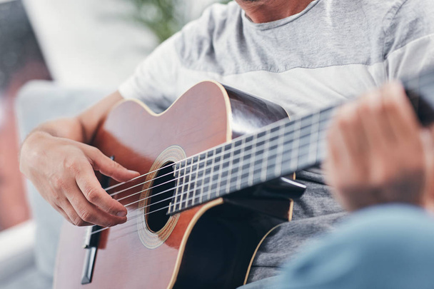 Hombre tocando la guitarra acústica en el salón
. - Foto, Imagen