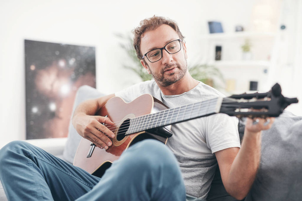 Adam oturma odasında akustik gitar çalıyor.. - Fotoğraf, Görsel