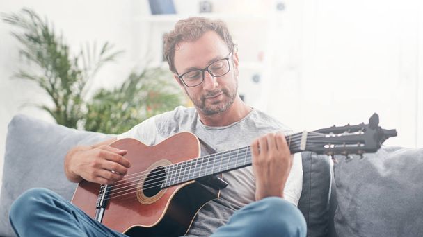 Homem tocando guitarra acústica na sala de estar
. - Foto, Imagem