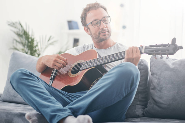Man playing acoustic guitar in the living room. - Photo, image