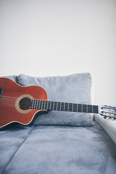Guitarra acústica em uma sala de estar sofá / sofá
. - Foto, Imagem
