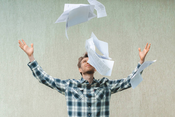 молодий стресовий чоловік кидає збиті паперові файли в повітрі, концепція свободи
 - Фото, зображення