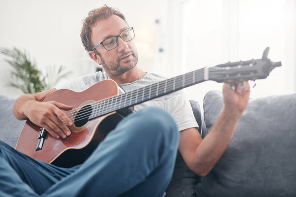 Adam oturma odasında akustik gitar çalıyor.. - Fotoğraf, Görsel