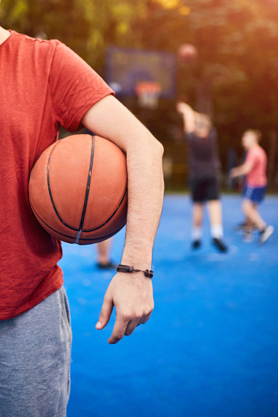 Мужчина держит баскетбольный мяч на городской площадке
. - Фото, изображение