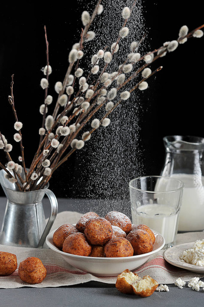 Cottage cheese balls, toasted in oil. Behind the plate is a vase with willow twigs. In the frame there is a saucer with cottage cheese, a glass and a jug with milk. Closeup. Vertical frame orientation - Photo, image