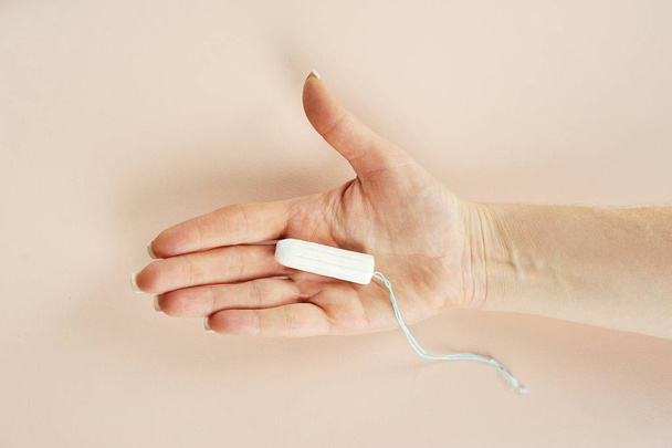 Hygienic tampon on the female palm. Close-up. Light background. View from above. - Φωτογραφία, εικόνα