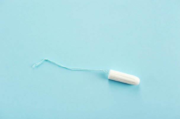 Hygienic tampon on a blue background. In the frame free space for placing text. Close-up. - Foto, Imagem
