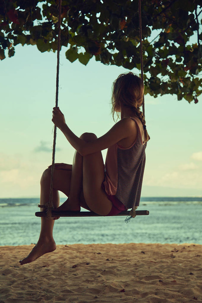Jeune femme balançant sur une plage tropicale sablonneuse
. - Photo, image