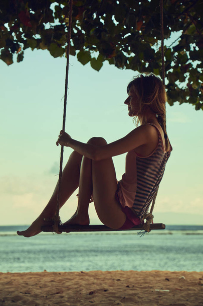 Jeune femme balançant sur une plage tropicale sablonneuse
. - Photo, image