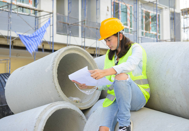 Ingenieros asiáticos mujeres mirando plano en el sitio de construcción
 - Foto, imagen