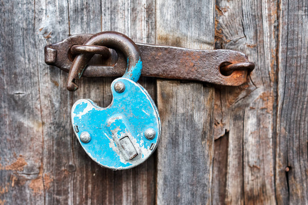 Vieux cadenas bleu rouillé déverrouillé sur porte en bois
 - Photo, image