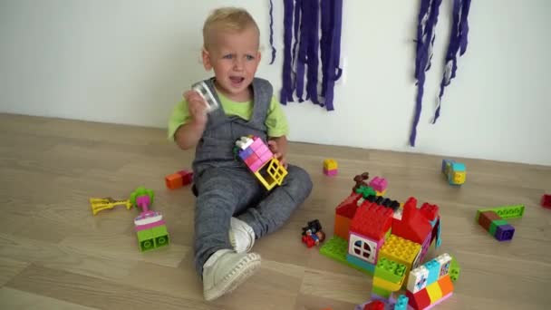 Wicked boy child play with colorful constructor bricks on floor. Gimbal motion - Metraje, vídeo