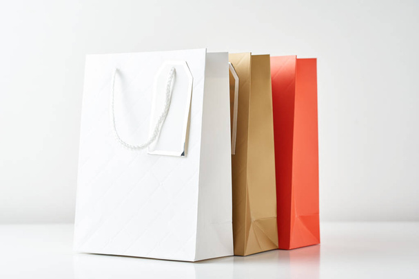 Τρεις πολύχρωμες σακούλες αγορών χαρτιού σε λευκό φόντο - Φωτογραφία, εικόνα