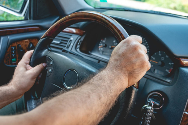 Male driver hands holding steering wheel. Man driving a car. - 写真・画像