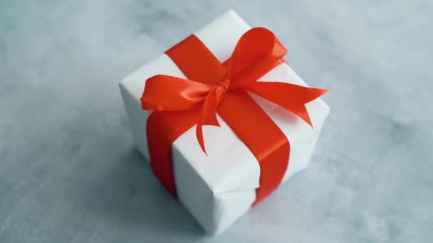 Белая подарочная коробка с красной шелковой лентой вращается. Подарочная коробка на Рождество, черную пятницу и другие праздники. Закрыть 4k отснятый материал
. - Кадры, видео