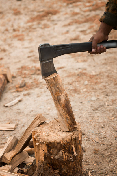 Ein asiatischer Mann hackt Holz. Brennholz auf dem Boden - Foto, Bild