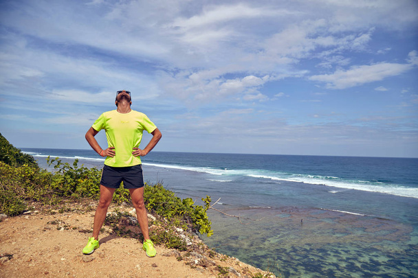Sportsman rozciąganie na tropikalnym egzotycznym klifie w pobliżu oceanu. - Zdjęcie, obraz