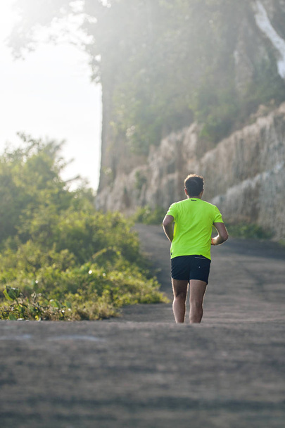 Ember jogging a lejtőn/dombra külvárosában hegyi úton. - Fotó, kép