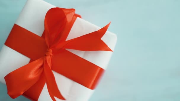 White gift box with red silk ribbon rotating.  Gift box for Christmas, black friday and other holidays.  Close up 4k footage. - Footage, Video
