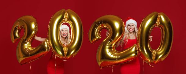 Happy New Year. Women tweens With Balloons Celebrating At Christmas Party. Portrait Of Beautiful Smiling Girls In fashion Dresses Throwing Confetti, Having Fun With Gold 2020 Balloons On red Background.  - Photo, image